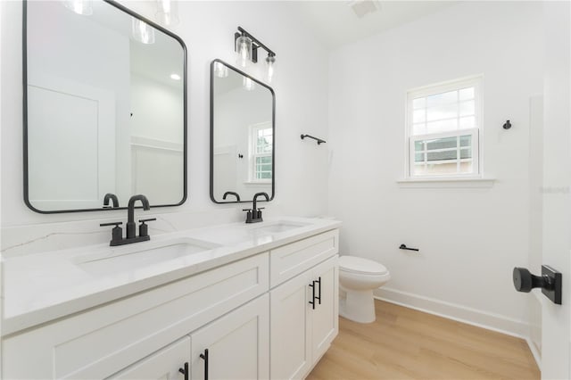 bathroom with toilet, baseboards, a sink, and wood finished floors