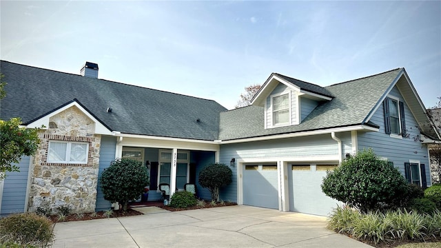 view of front of property with a garage, stone siding, concrete driveway, and roof with shingles