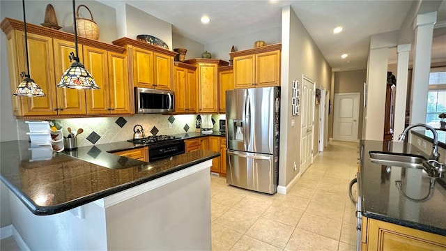 kitchen featuring decorative backsplash, appliances with stainless steel finishes, brown cabinets, a peninsula, and a sink