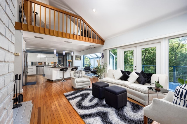 living room with high vaulted ceiling, french doors, and hardwood / wood-style flooring