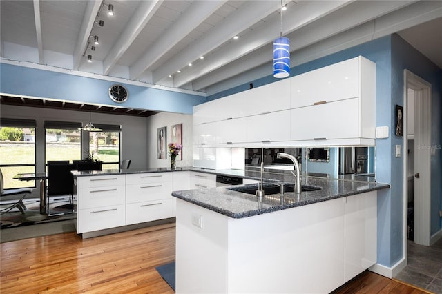 kitchen featuring a peninsula, a sink, white cabinets, dark stone counters, and modern cabinets