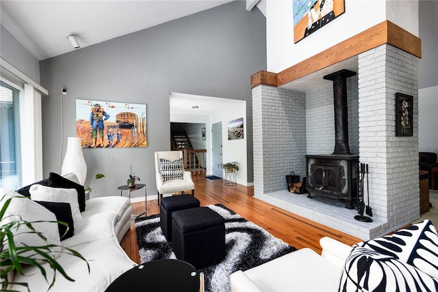 living area featuring high vaulted ceiling, wood finished floors, a wood stove, and baseboards