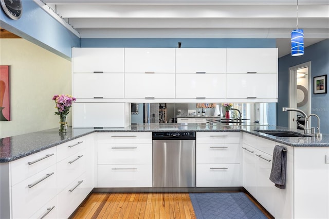 kitchen featuring white cabinetry, a sink, dark stone countertops, modern cabinets, and dishwasher