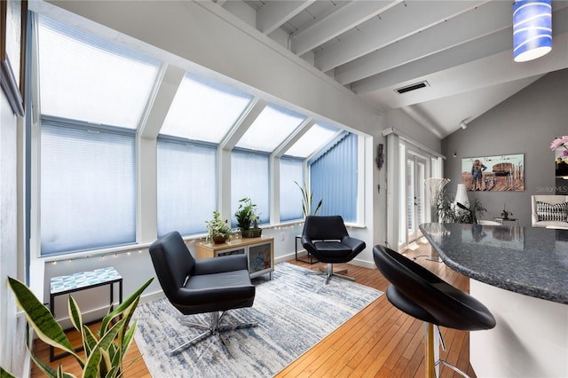 sitting room featuring a sunroom, visible vents, vaulted ceiling, baseboards, and hardwood / wood-style floors