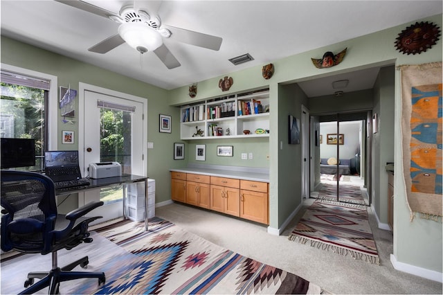 office area with a ceiling fan, visible vents, light carpet, and baseboards