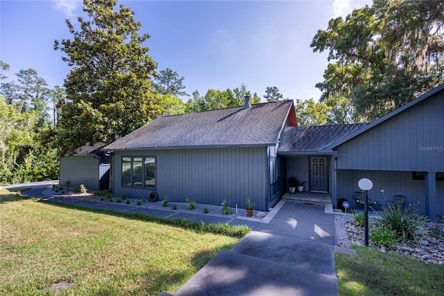 mid-century home featuring a front lawn and roof with shingles