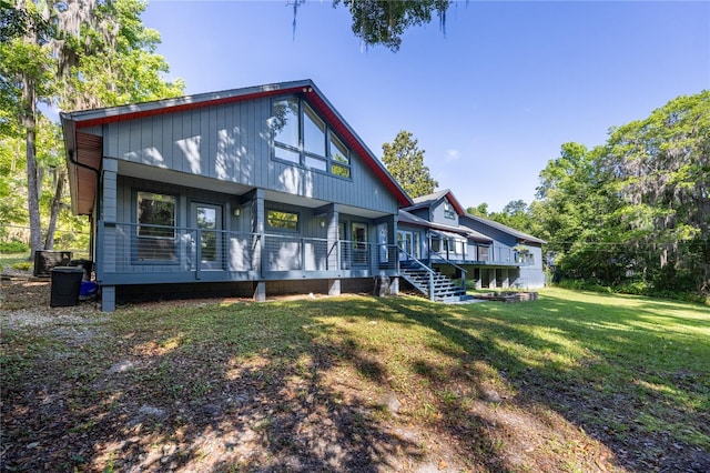 rear view of property with covered porch and a lawn