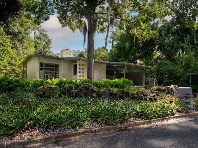 mid-century home with brick siding and a chimney