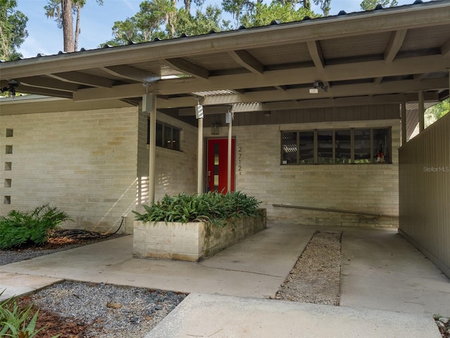 property entrance featuring an attached carport and brick siding