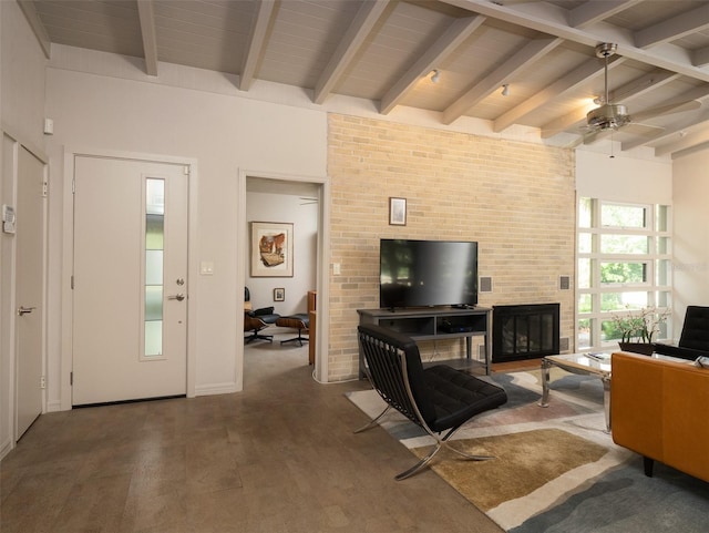 living area featuring ceiling fan, a glass covered fireplace, wood finished floors, and beamed ceiling