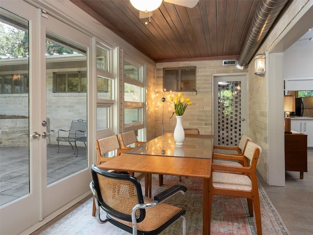 dining room with wood ceiling, visible vents, and brick wall