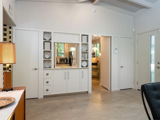 kitchen with open shelves, beamed ceiling, freestanding refrigerator, and white cabinets