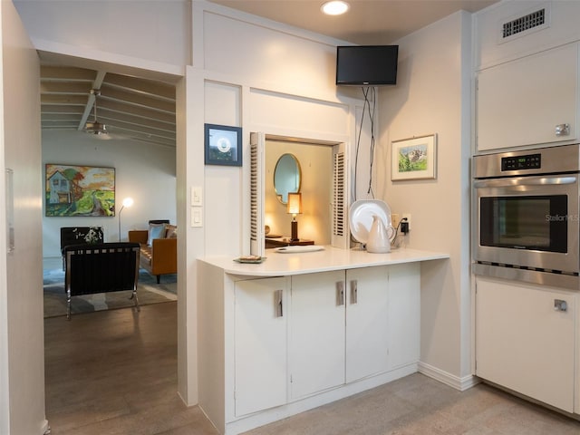 kitchen featuring light countertops, visible vents, white cabinets, stainless steel oven, and wood finished floors