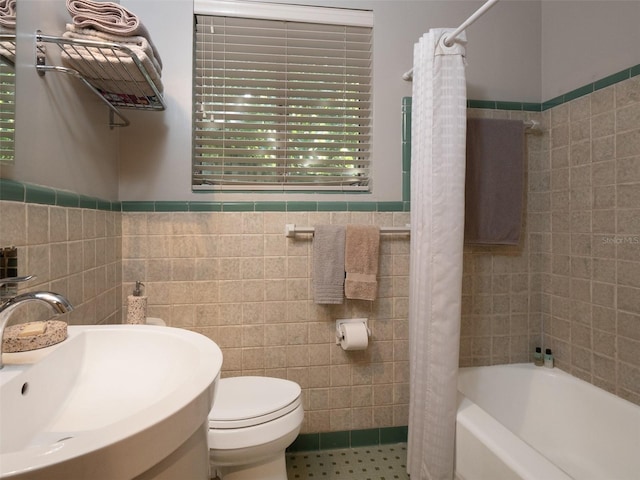 bathroom featuring toilet, shower / tub combo with curtain, a sink, tile patterned flooring, and tile walls