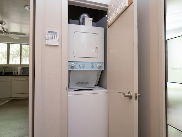 clothes washing area featuring stacked washer and dryer, ceiling fan, laundry area, and a sink