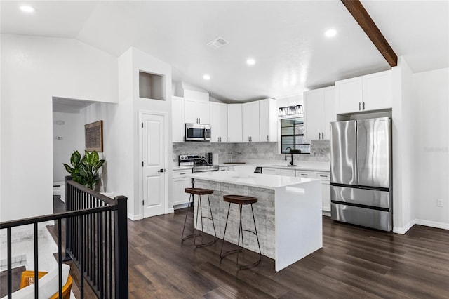 kitchen with visible vents, vaulted ceiling, light countertops, appliances with stainless steel finishes, and a center island