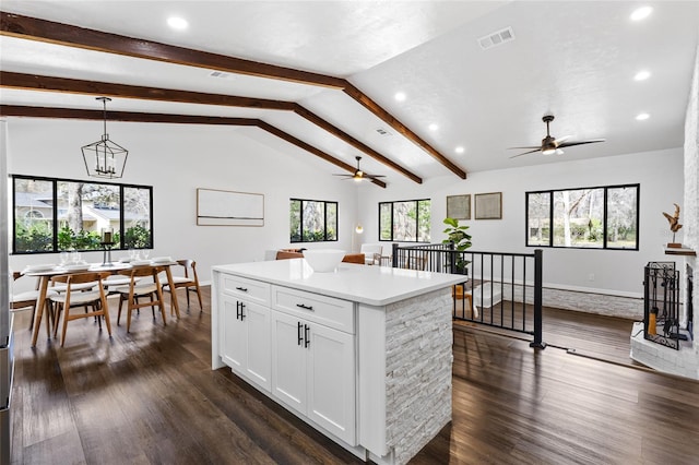 kitchen featuring dark wood-style floors, light countertops, white cabinets, and vaulted ceiling with beams