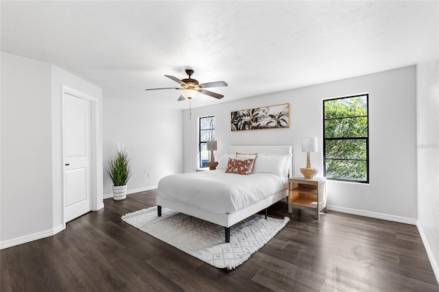 bedroom featuring ceiling fan, multiple windows, baseboards, and dark wood finished floors