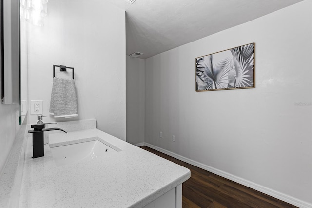 bathroom with visible vents, a sink, baseboards, and wood finished floors