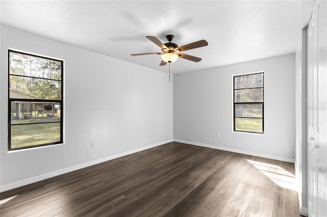 spare room with baseboards, dark wood finished floors, and a ceiling fan