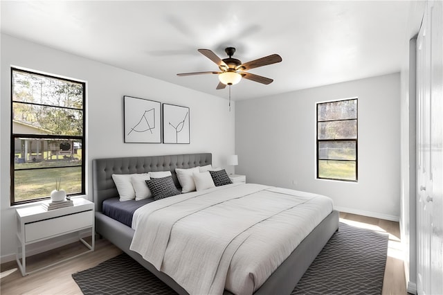 bedroom featuring multiple windows, light wood-style flooring, and baseboards