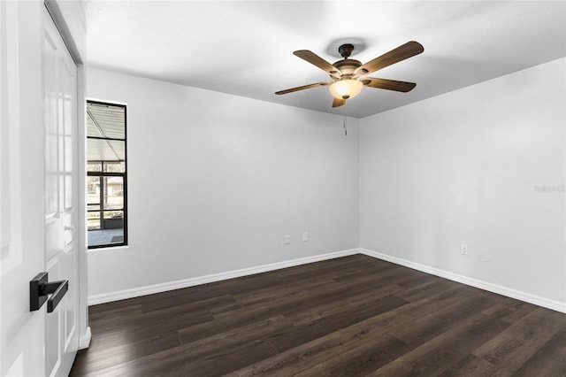 spare room with ceiling fan, dark wood-type flooring, and baseboards