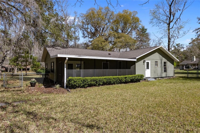 back of house featuring a shingled roof, fence, a sunroom, a lawn, and a gate