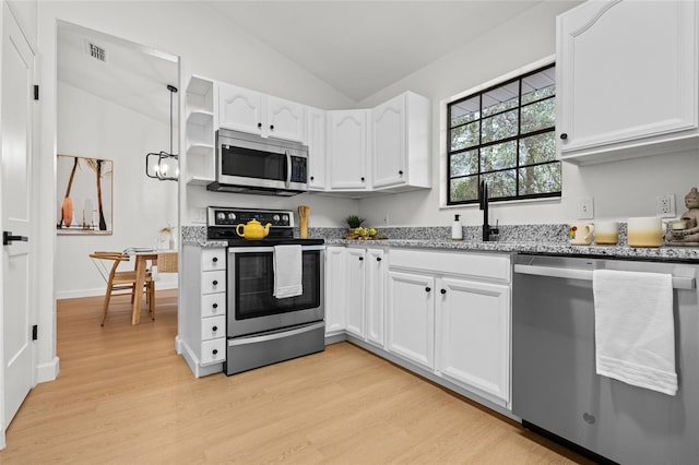 kitchen featuring visible vents, lofted ceiling, appliances with stainless steel finishes, light stone counters, and white cabinetry