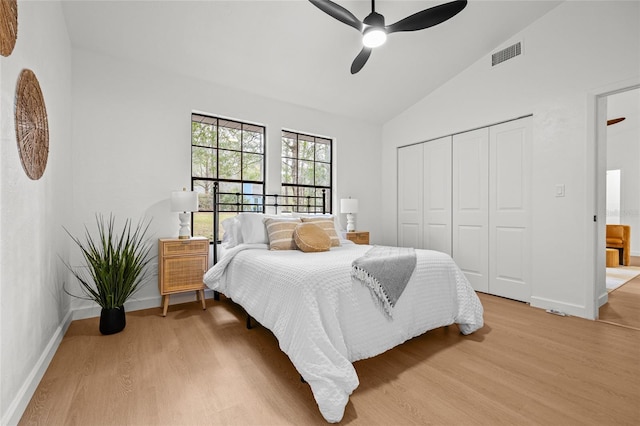 bedroom with light wood-style floors, lofted ceiling, a closet, and visible vents