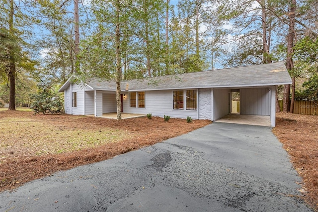 ranch-style home featuring driveway, an attached carport, and fence