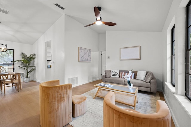 living area with lofted ceiling, visible vents, and light wood-style floors