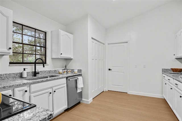 kitchen with light stone counters, light wood-type flooring, stainless steel dishwasher, white cabinetry, and a sink