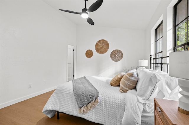 bedroom featuring vaulted ceiling, wood finished floors, a ceiling fan, and baseboards