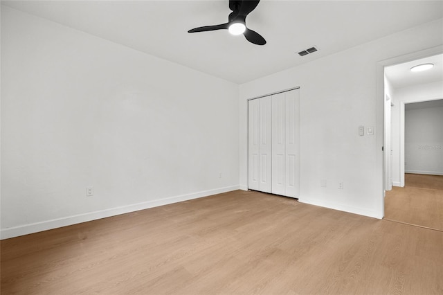 unfurnished bedroom featuring a closet, visible vents, baseboards, and light wood finished floors