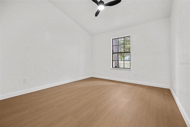 empty room featuring vaulted ceiling, wood finished floors, a ceiling fan, and baseboards