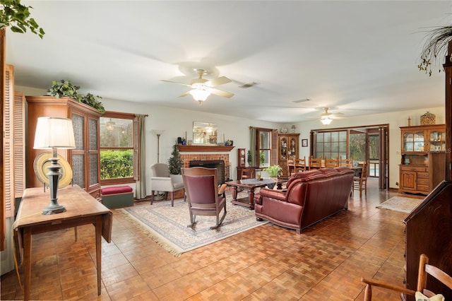 living area featuring a wealth of natural light, visible vents, a fireplace, and ceiling fan