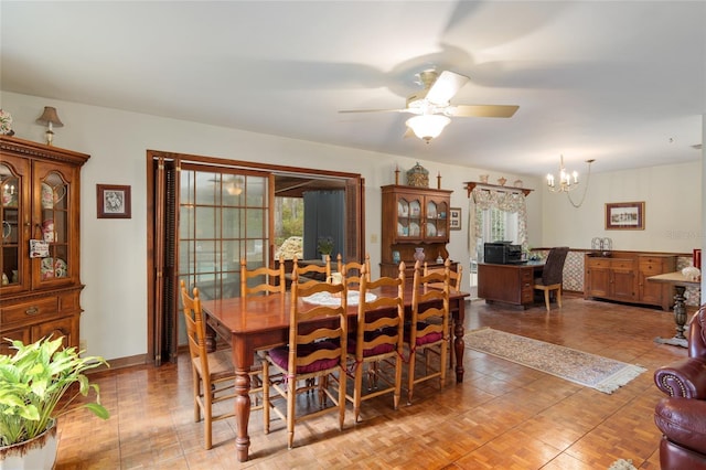 dining space featuring baseboards and ceiling fan with notable chandelier