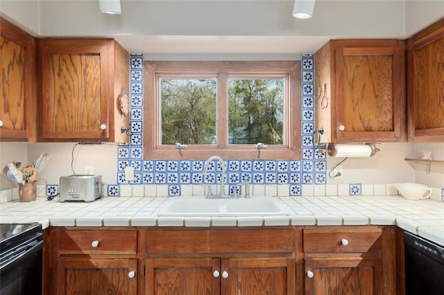 kitchen featuring black dishwasher, brown cabinetry, a sink, and light countertops