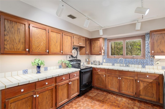 kitchen featuring brown cabinets, black electric range, visible vents, and a sink