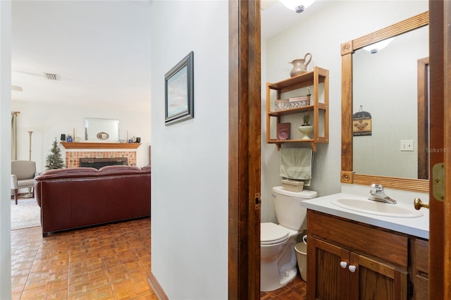 bathroom with a fireplace, visible vents, toilet, vanity, and ensuite bath