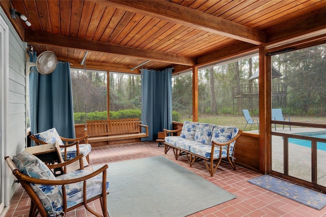 sunroom with wooden ceiling, beamed ceiling, and a view of trees