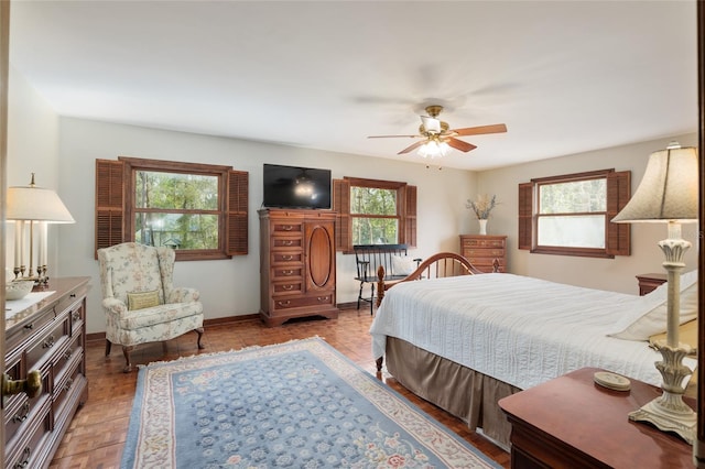 bedroom featuring a ceiling fan, multiple windows, and baseboards