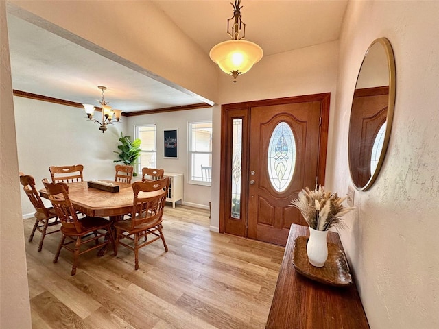 foyer with a chandelier, crown molding, light wood-style flooring, and baseboards