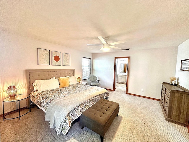 bedroom with ceiling fan, ensuite bathroom, light colored carpet, visible vents, and baseboards