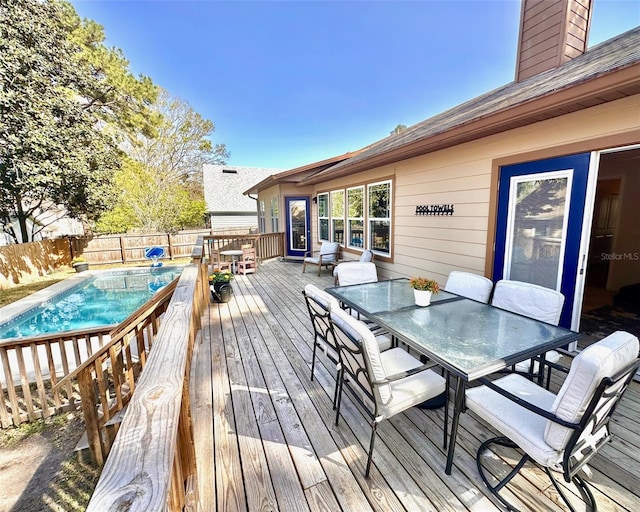 wooden terrace with a fenced backyard, outdoor dining area, and a fenced in pool