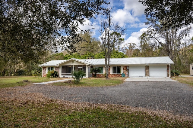 single story home featuring gravel driveway, a front lawn, a garage, and metal roof