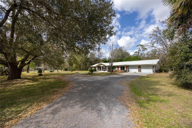 ranch-style home featuring driveway, a front lawn, and a garage