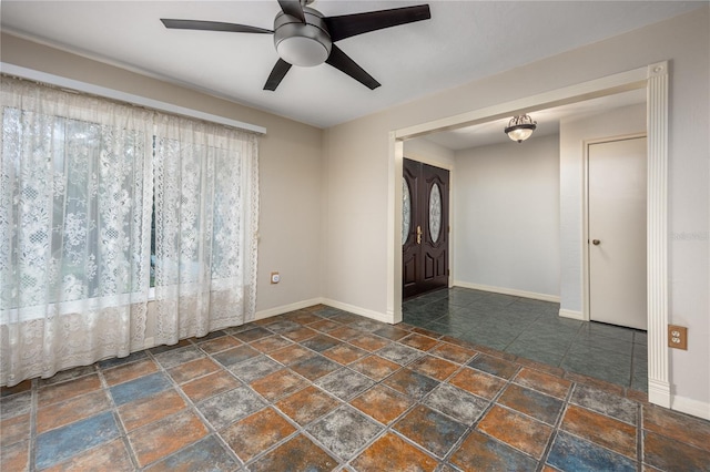 spare room featuring stone finish flooring, baseboards, and a ceiling fan