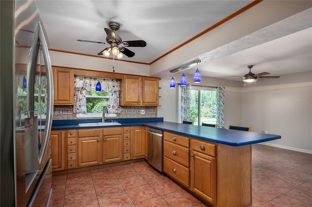 kitchen featuring a peninsula, ornamental molding, a sink, appliances with stainless steel finishes, and tasteful backsplash