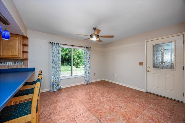 unfurnished dining area with light tile patterned floors, baseboards, and ceiling fan